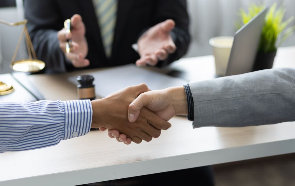 Two businessmen shaking hands in front of a business mediation attorney.