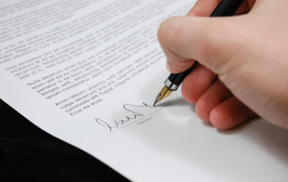 a person signing a document related to estate planning.